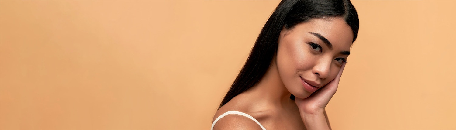 hand on face looking to side orange background