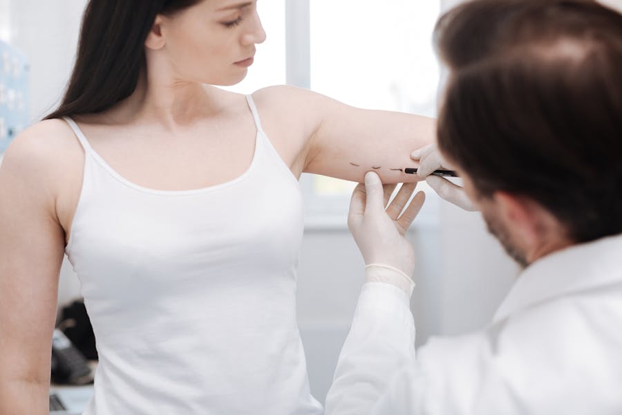 doctor drawing surgical lines on woman's arm