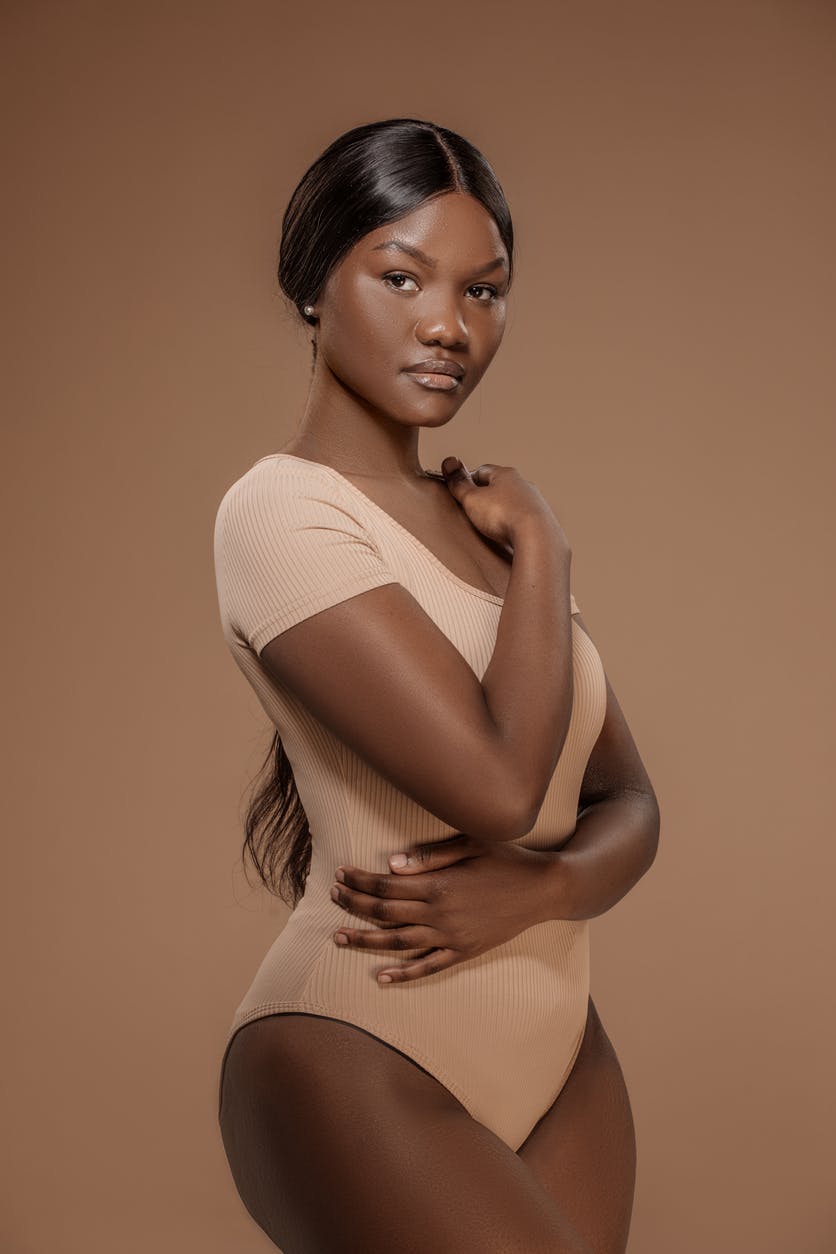 Beautiful Woman in a nude suit and hair pulled back showing her surgical body contour