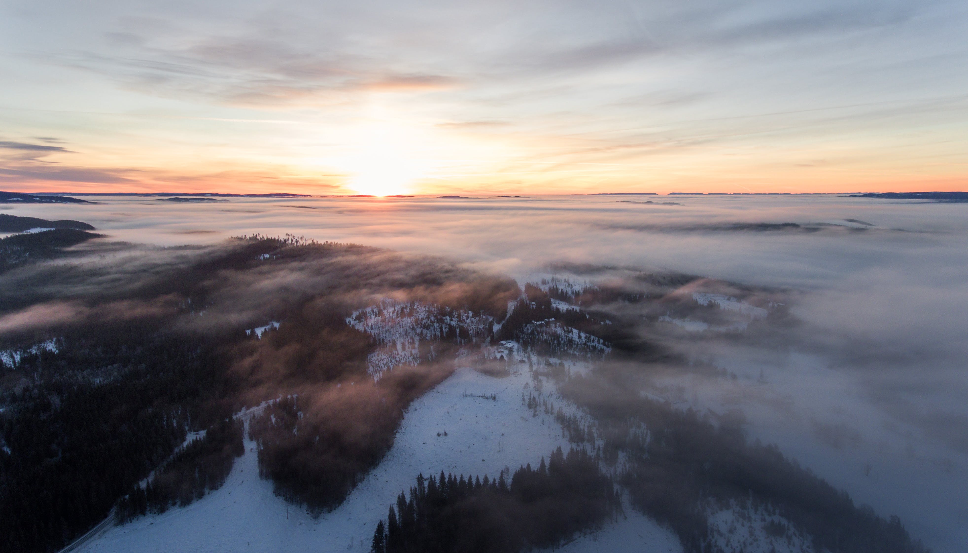 A cloudy sunset over a snowy forrest landscape.