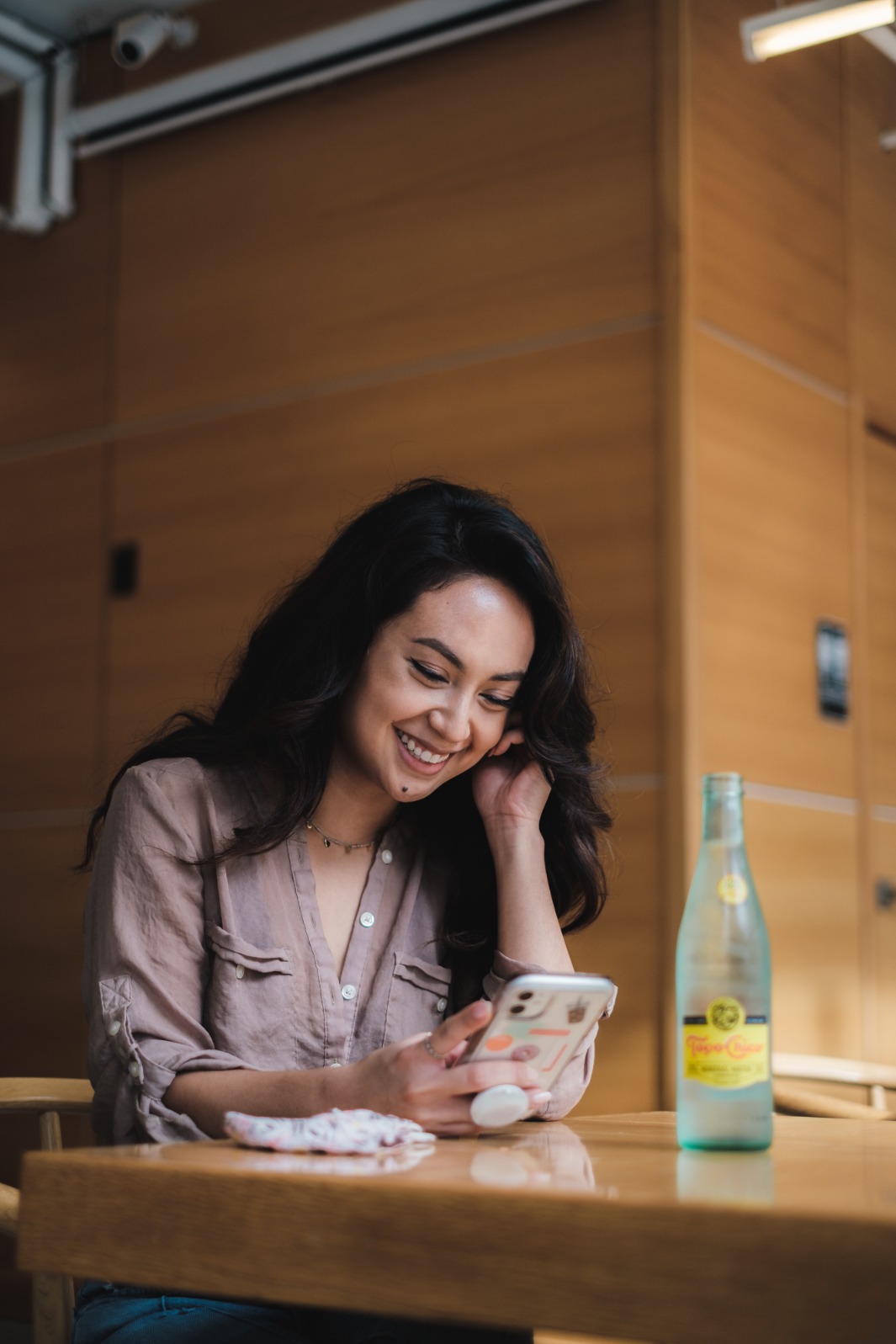 Image of a woman watching her phone smiling.