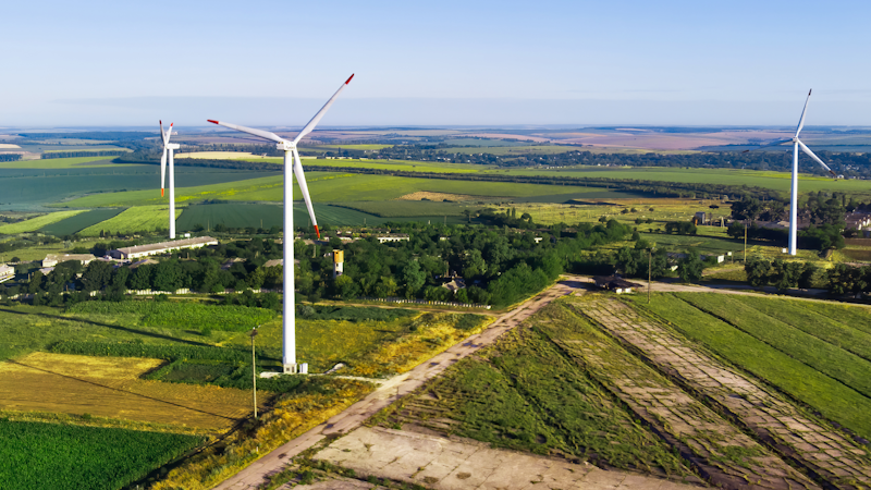Luftbild på vindkraftverk som står i ett svenskt åkerlandskap.