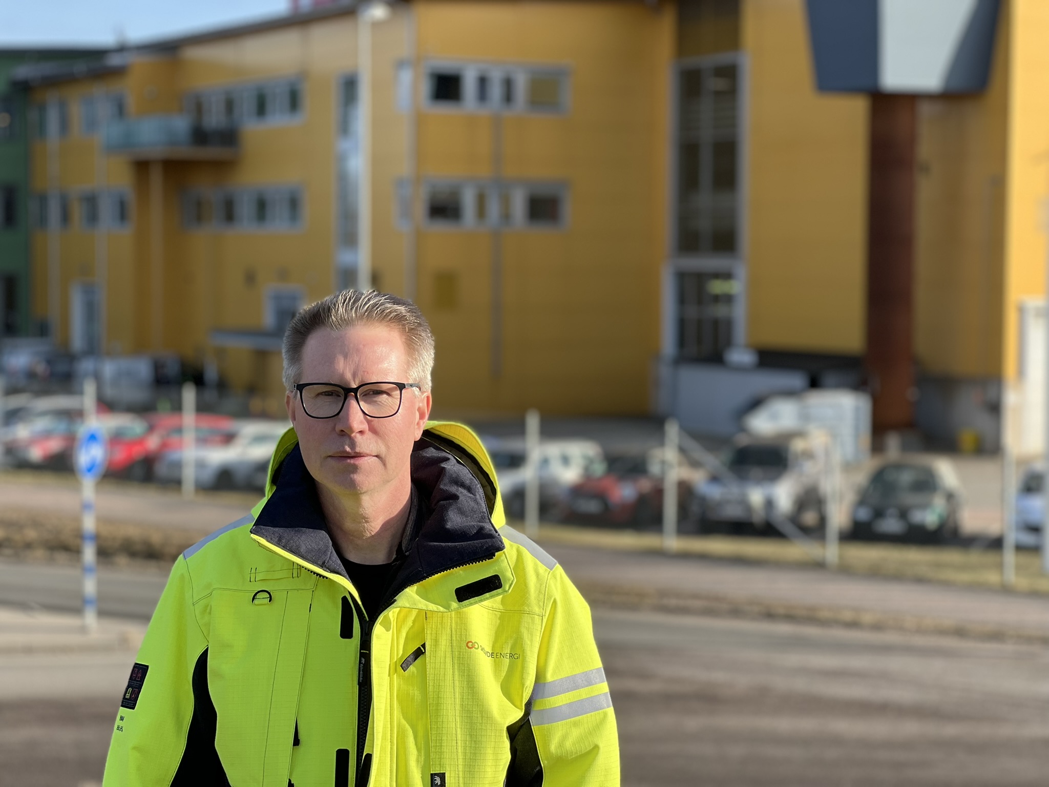 Man i gul varseljacka som står framför en gul fastighet.