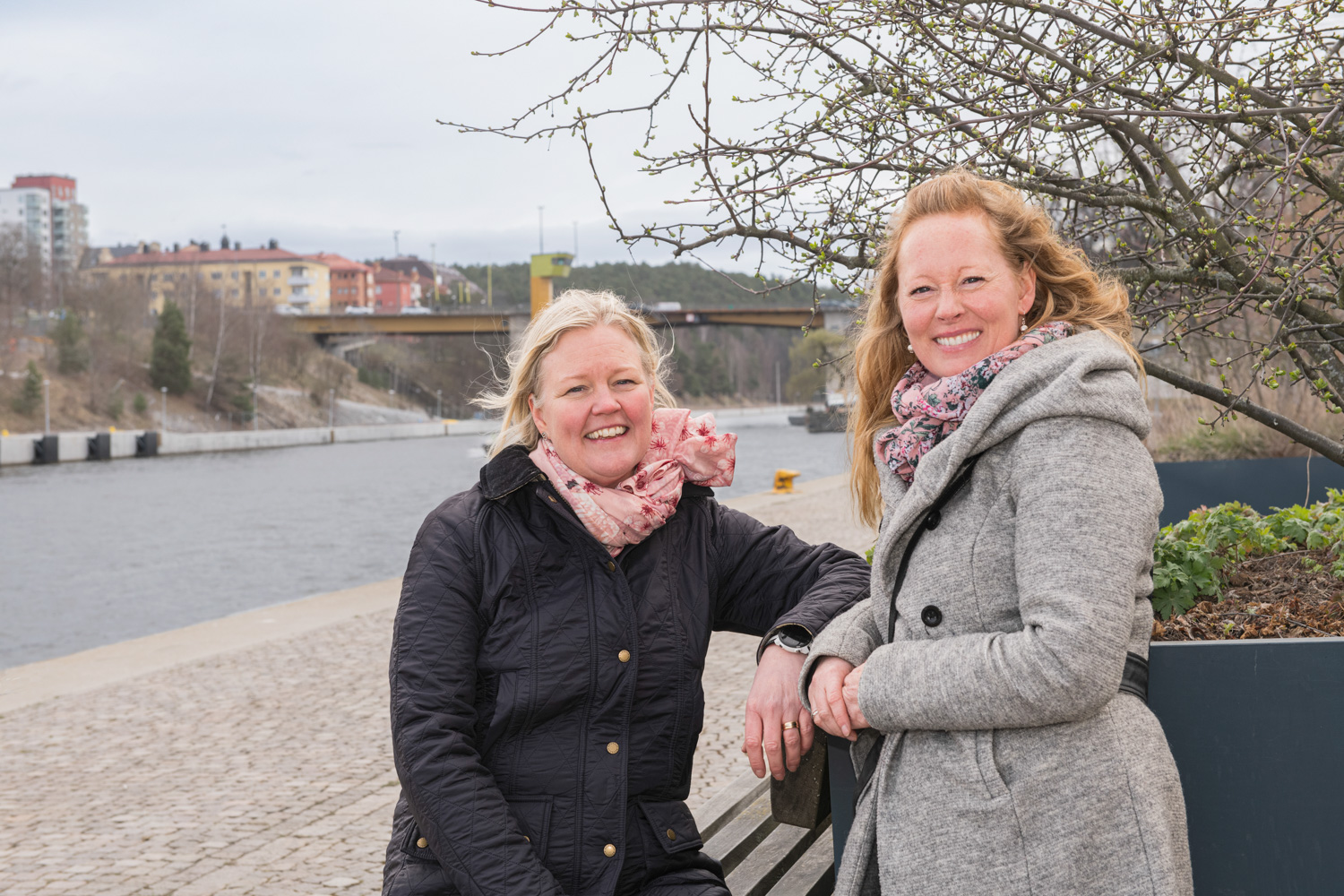 Sara Jannes, Telge AB och Christine Strandberg, Södertälje kommun. Två kvinnor som tittar in i kameran sittandes vid en bänk vid en kanal.