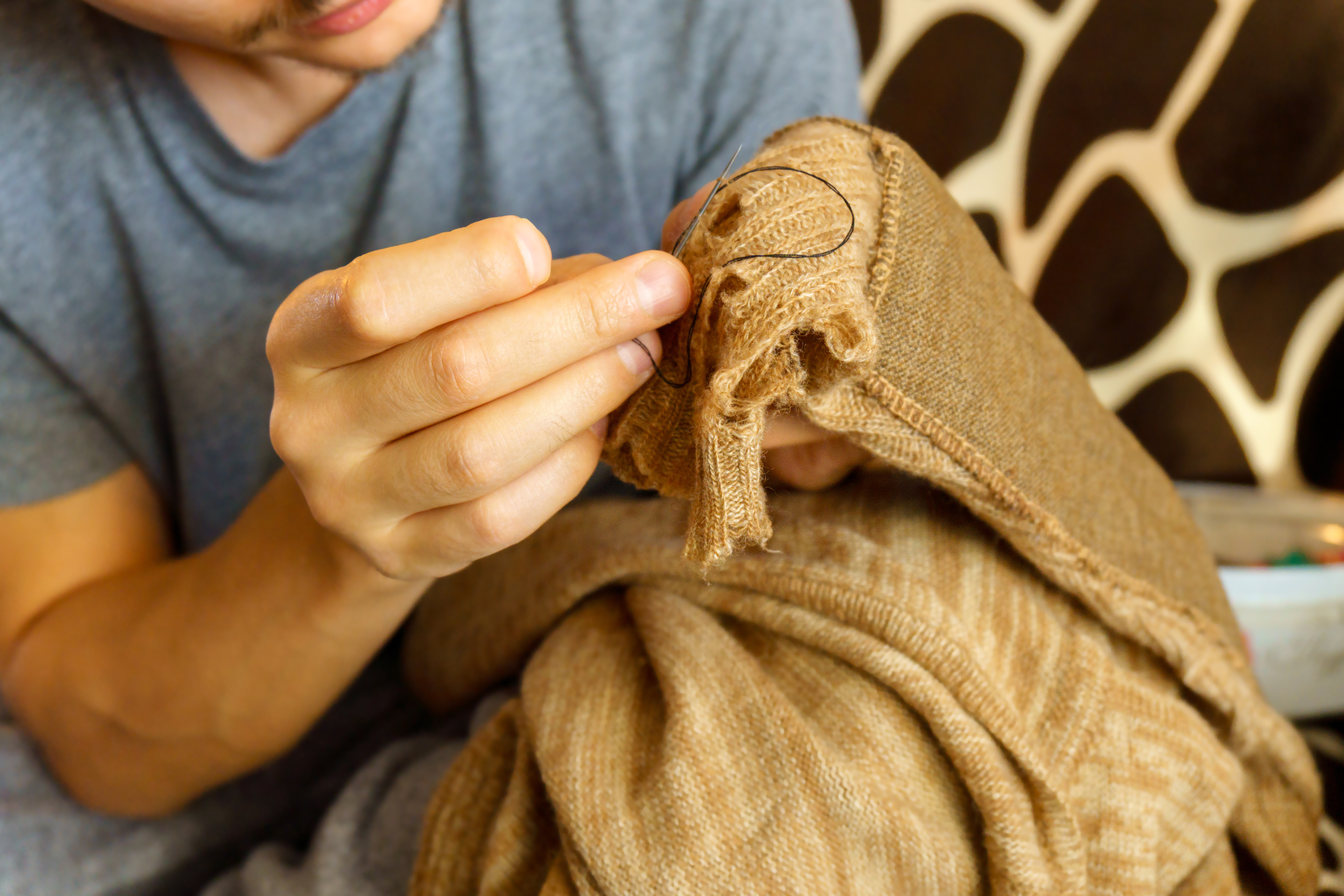Kille som lagar tröja med nål och tråd.