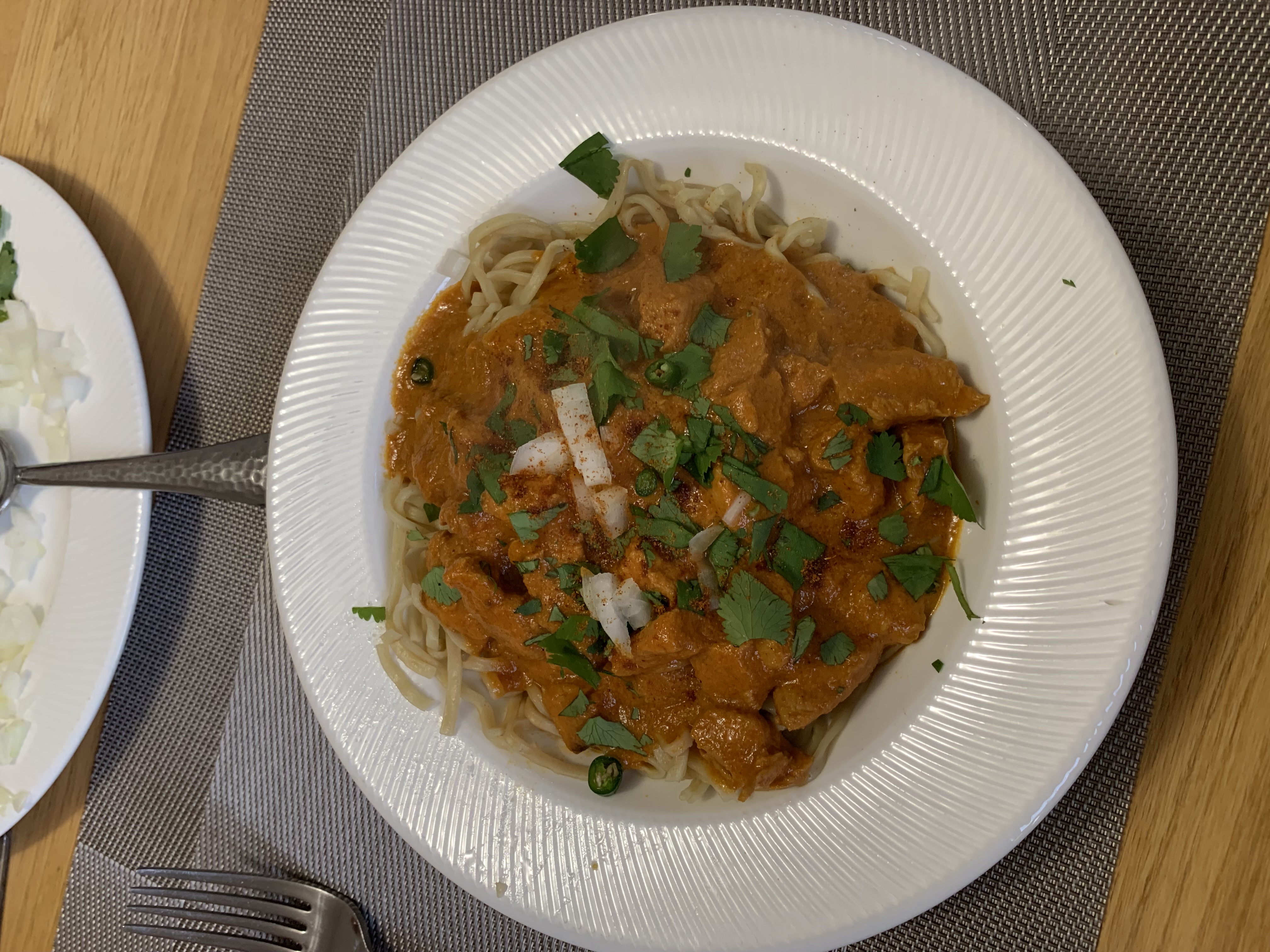 A bowl of khow suey topped with onion and coriander