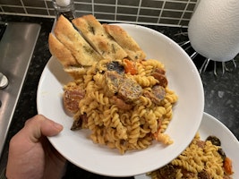 A bowl of chorizo pasta with garlic bread