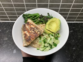 A sushi bowl made up of salmon, rice, broccoli, avacado and cucumber