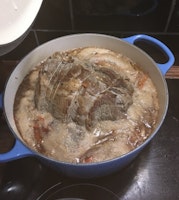 Beef brisket in a Dutch oven cooking in broth