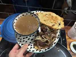 A beef sandwich with fried onions with french dip