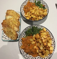 Two bowls of creamy sweet chilli chicken served with garlic bread