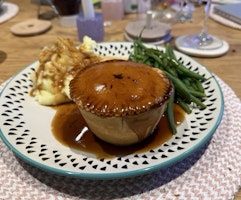 A plate with a braised beef pie, mash and green beans