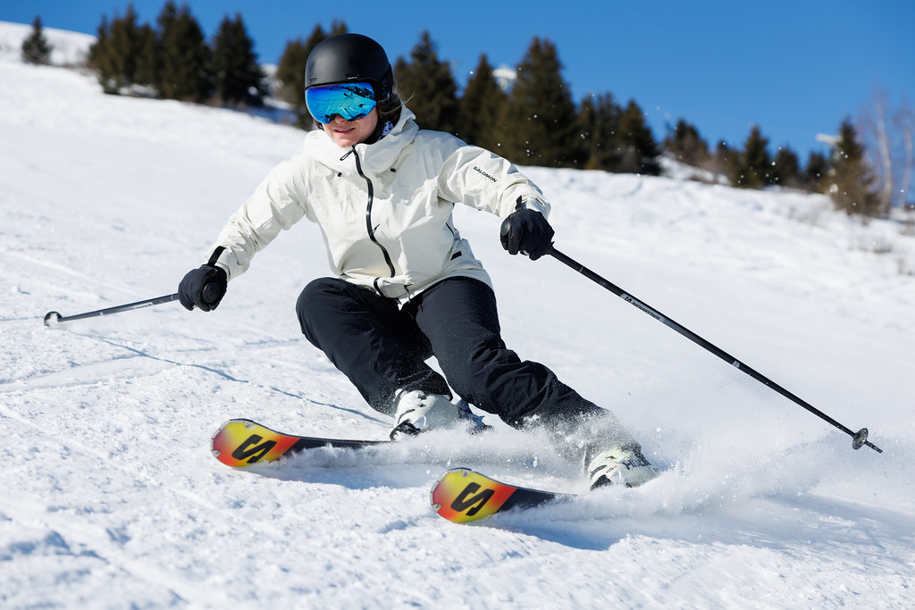 skieuse en plein virage, en arrière plan des sapins