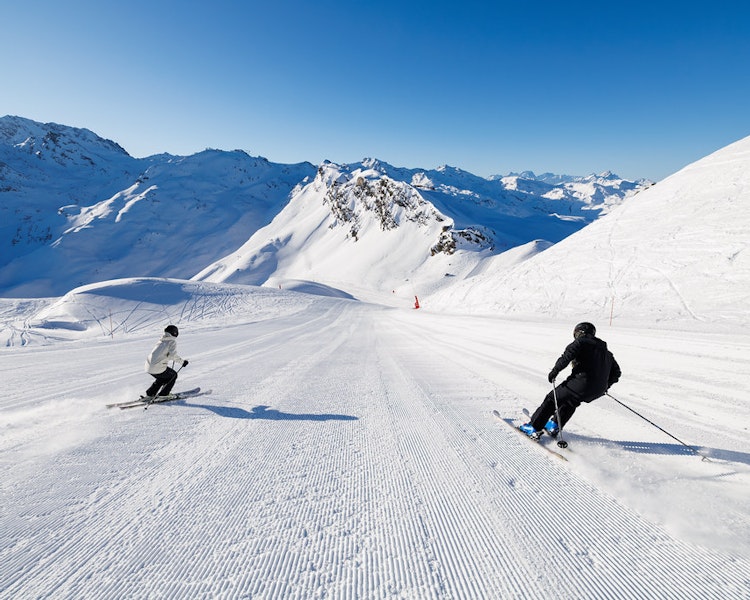 2 skiers skiing on a freshly groomed slope in Méribel