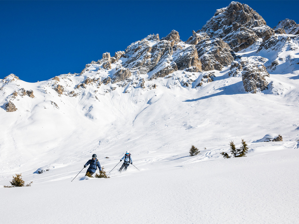 Two skiers descend a snow-covered slope off-piste in Méribel