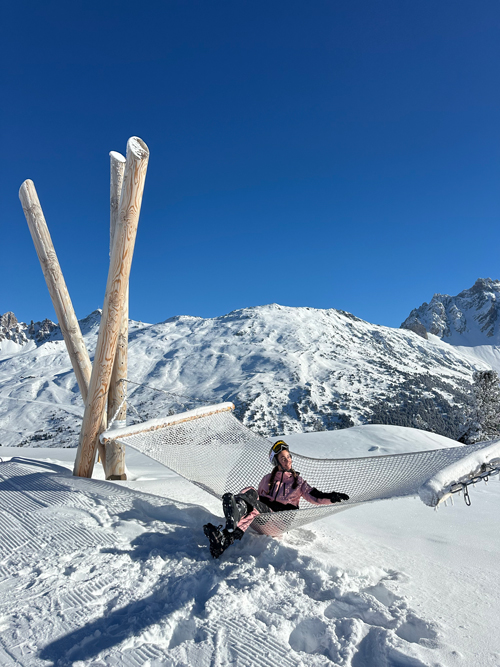 Une skieuse profite d’un moment de détente sur le hamac géant installé au-dessus de la neige du domaine skiable de Méribel-Mottaret