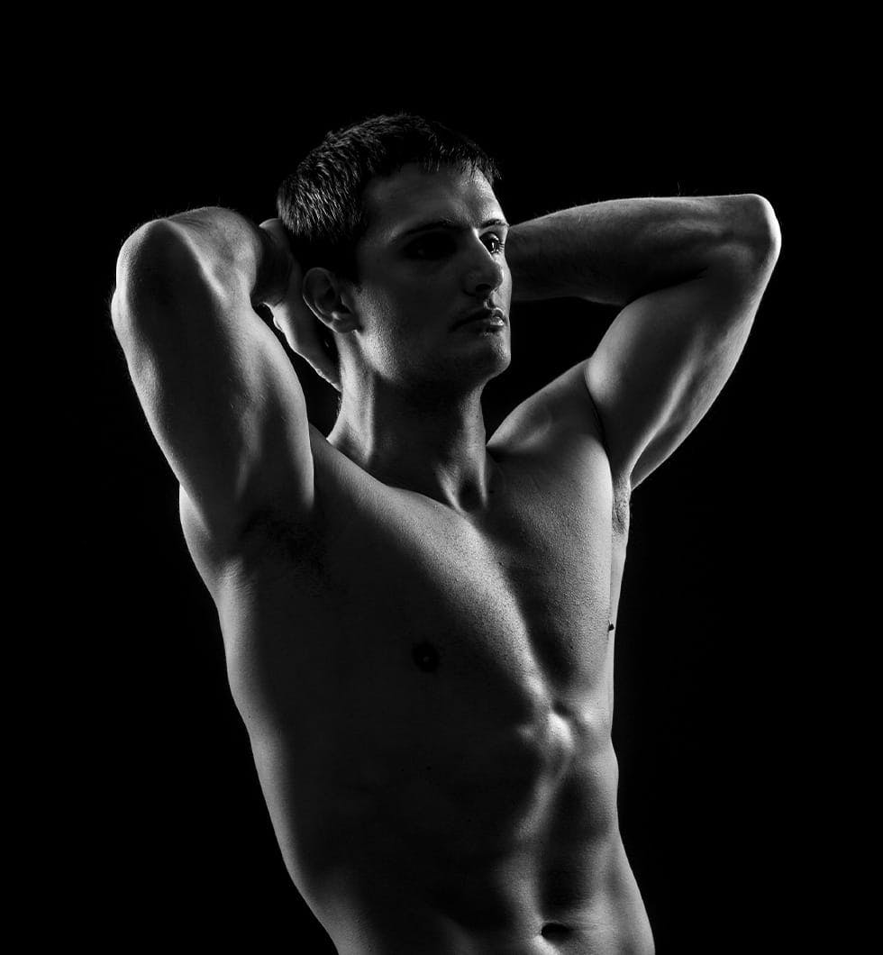shirtless man posing in front of a black background