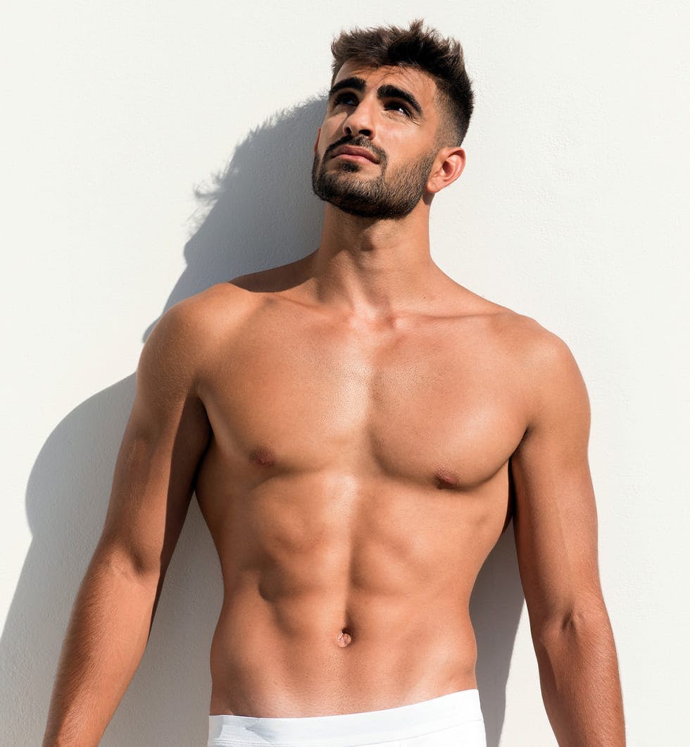 shirtless man leaning against white wall looking up
