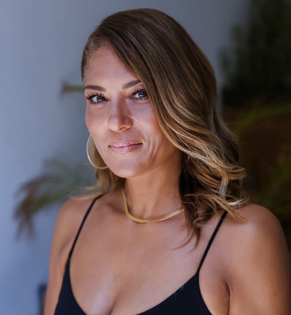 woman in a black top and gold necklace with a smile