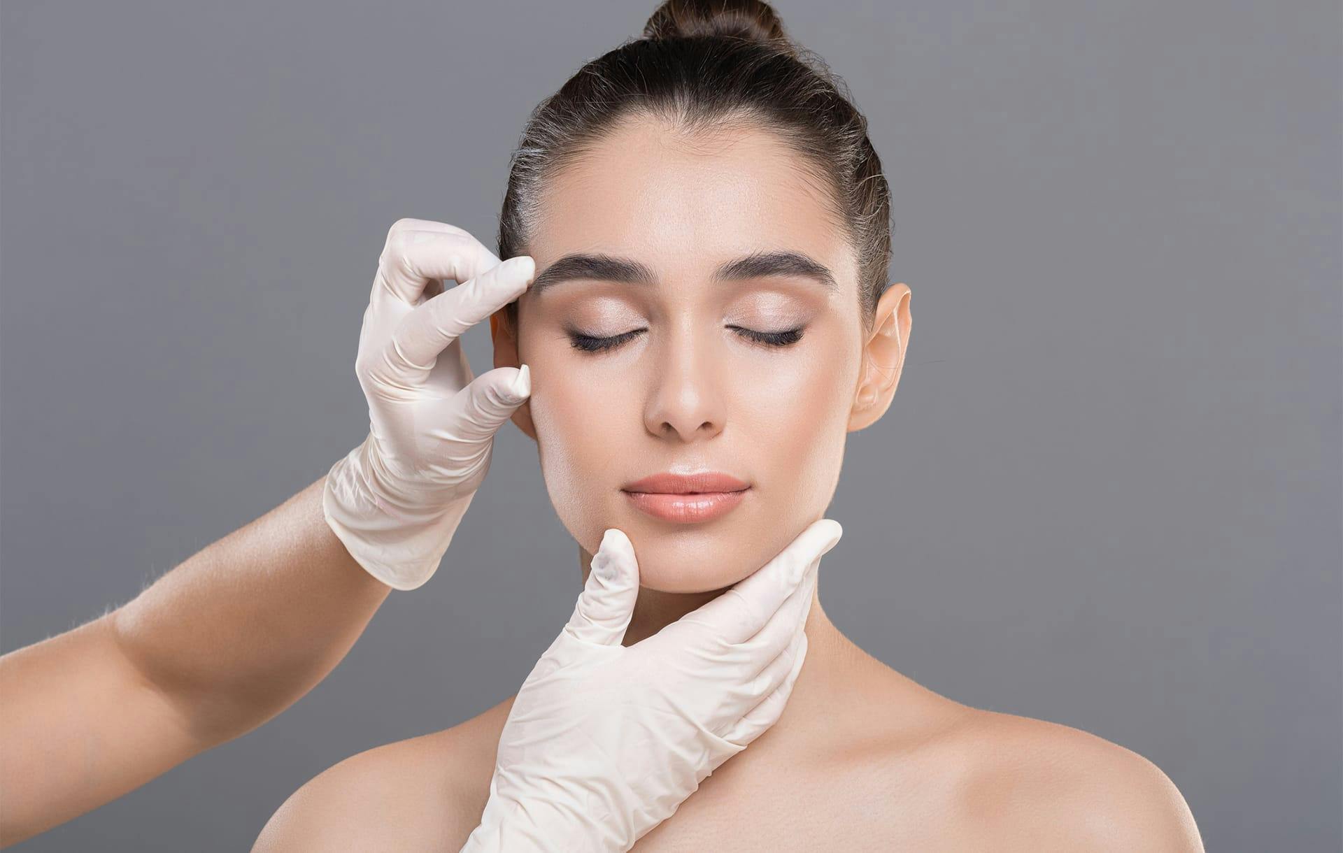 gloved hands touching a womans face