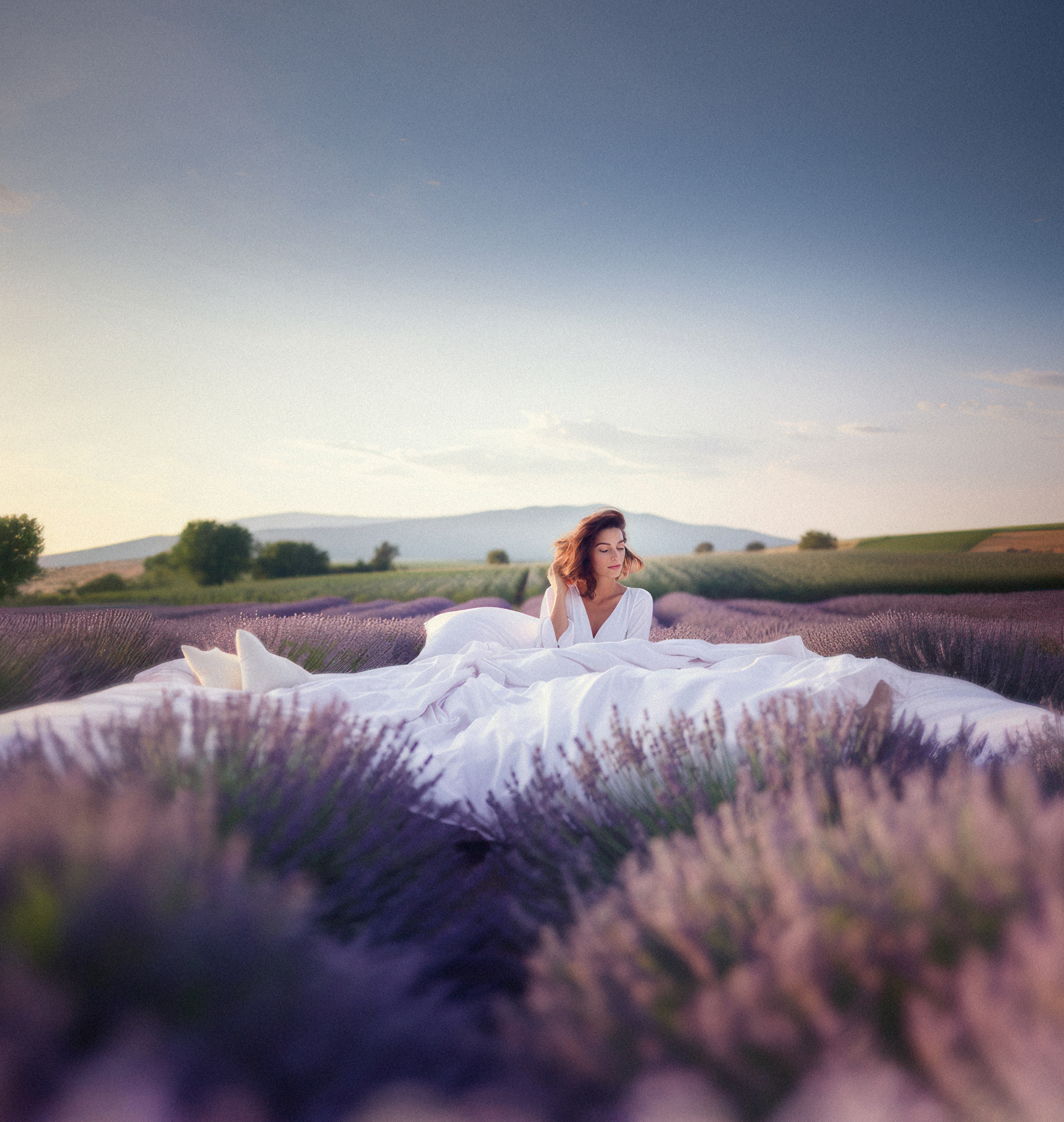 Vrouw in witte lakens op toscaans lanschap