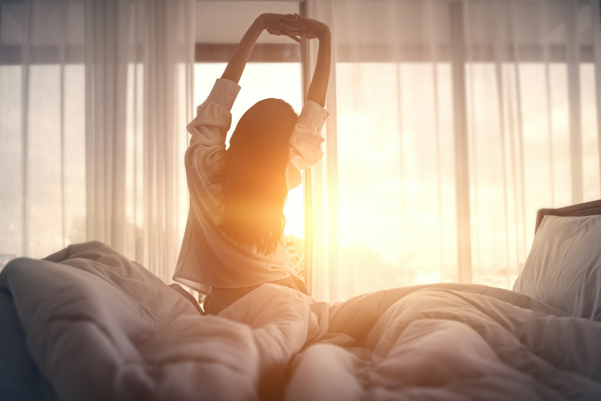 Vrouw die wakker wordt in de ochtend in gewassen beddengoed