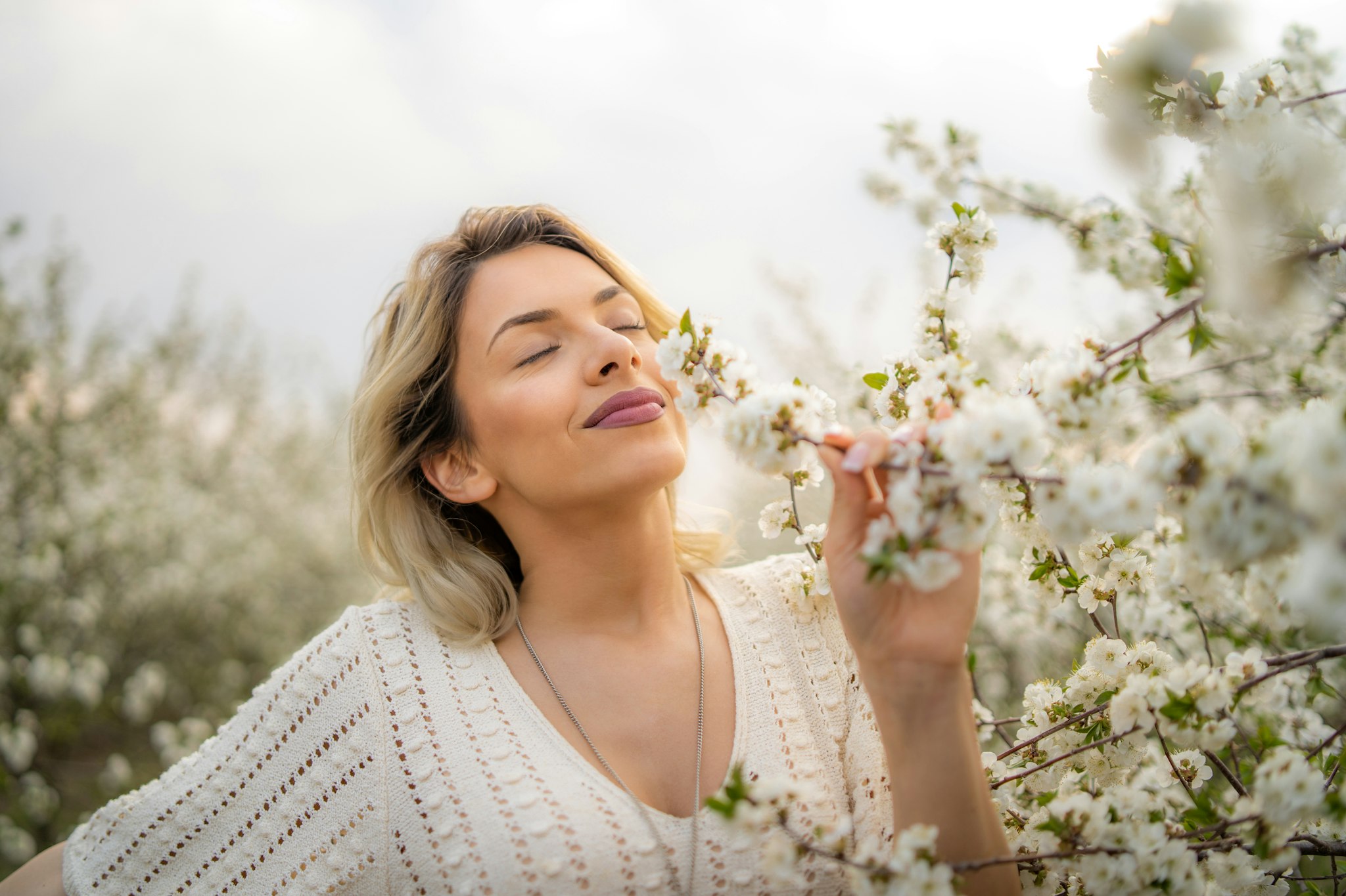 Vrouw ruikend aan heerlijk geurende bloemen, white musk