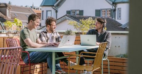 Drei Mitarbeiter von smartive sitzen mit ihren Laptops auf der sonnigen Dachterrasse von smartive in St. Gallen