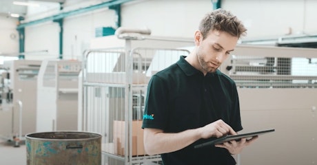 Ein Mitarbeiter von Spühl in einer Fabrikhalle bei der Bedienung eines Tablets