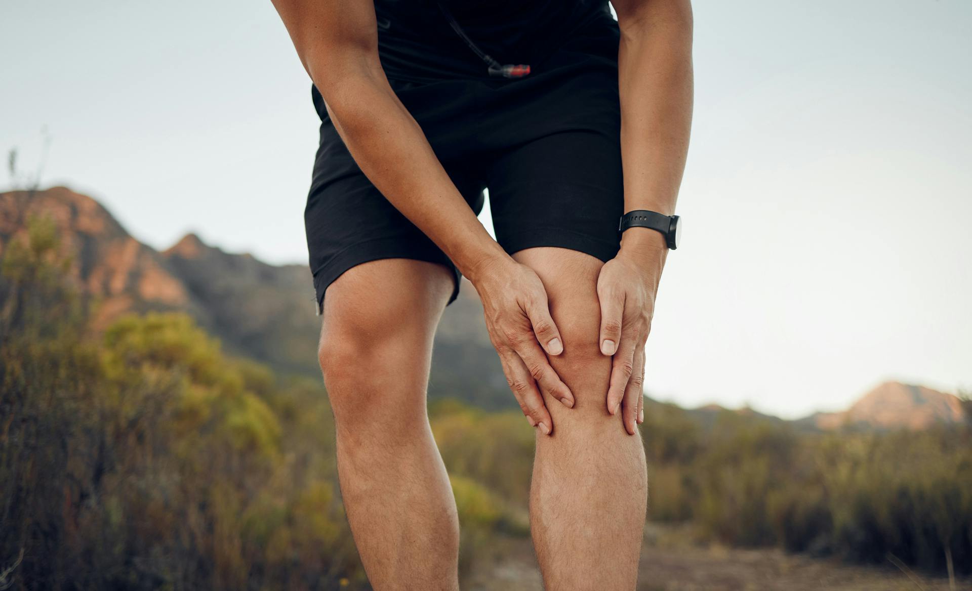 man holding knee while on hike