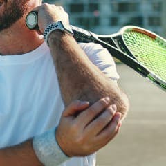 person holding their elbow while playing tennis