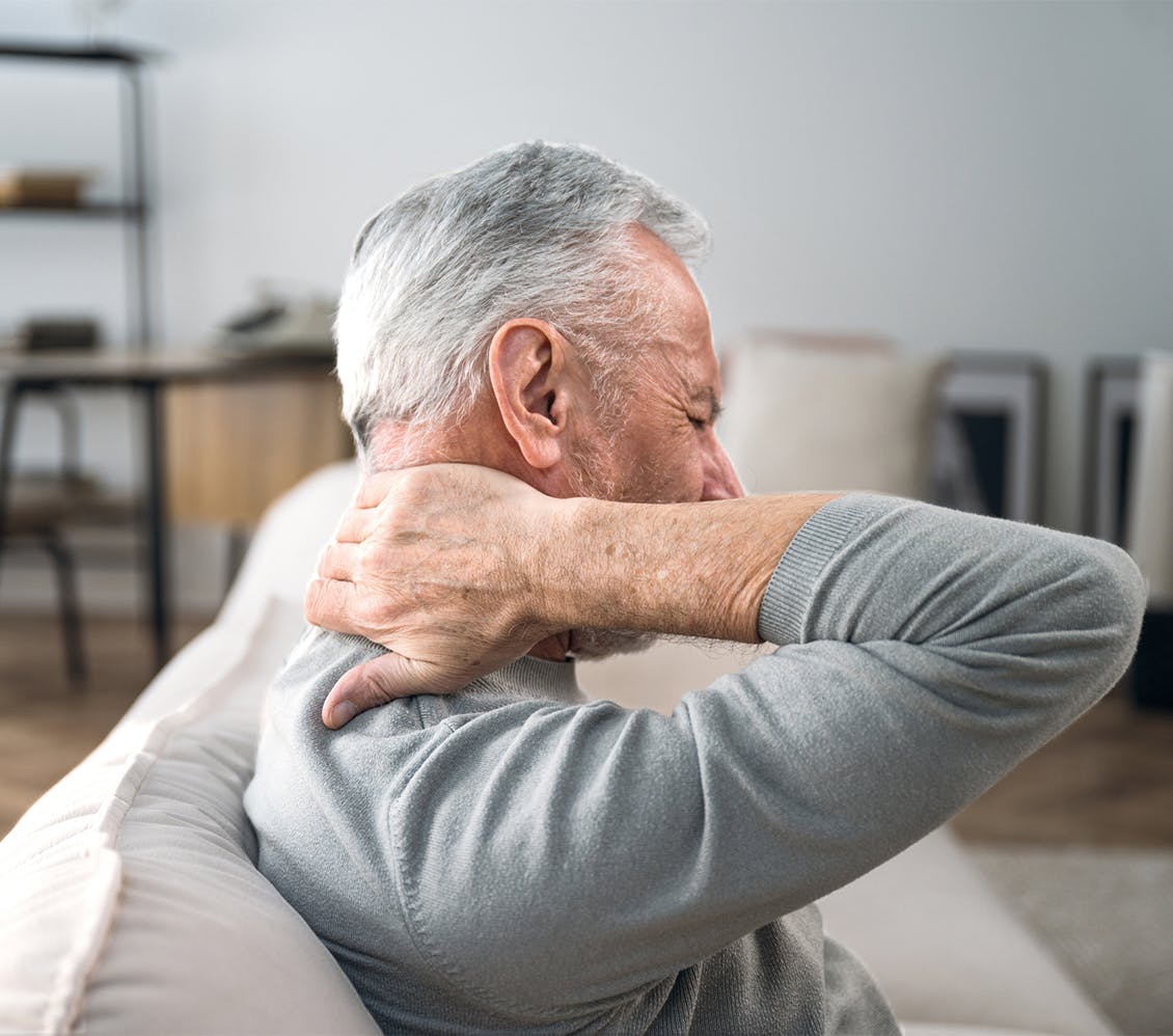 man holding back of neck in discomfort