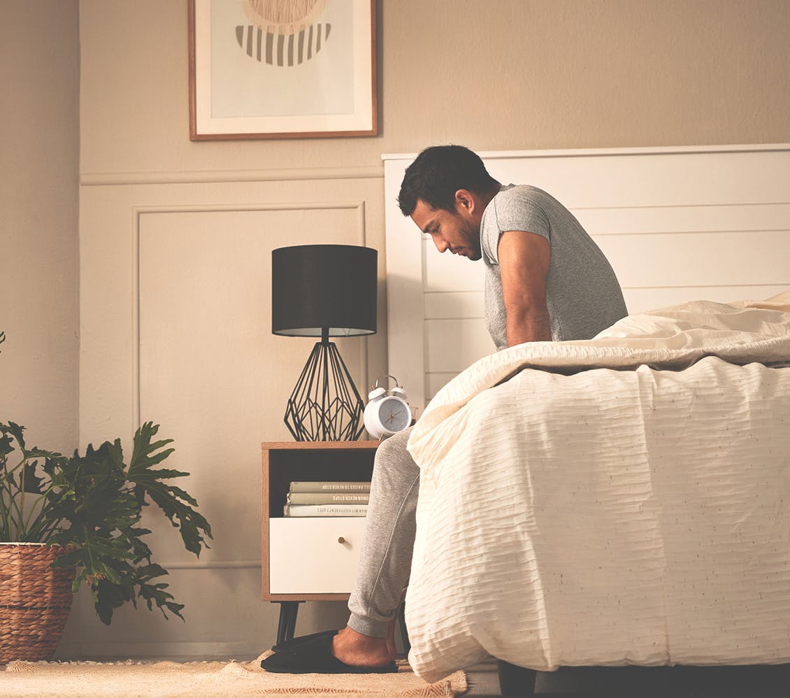 person sitting on edge of the bed in discomfort