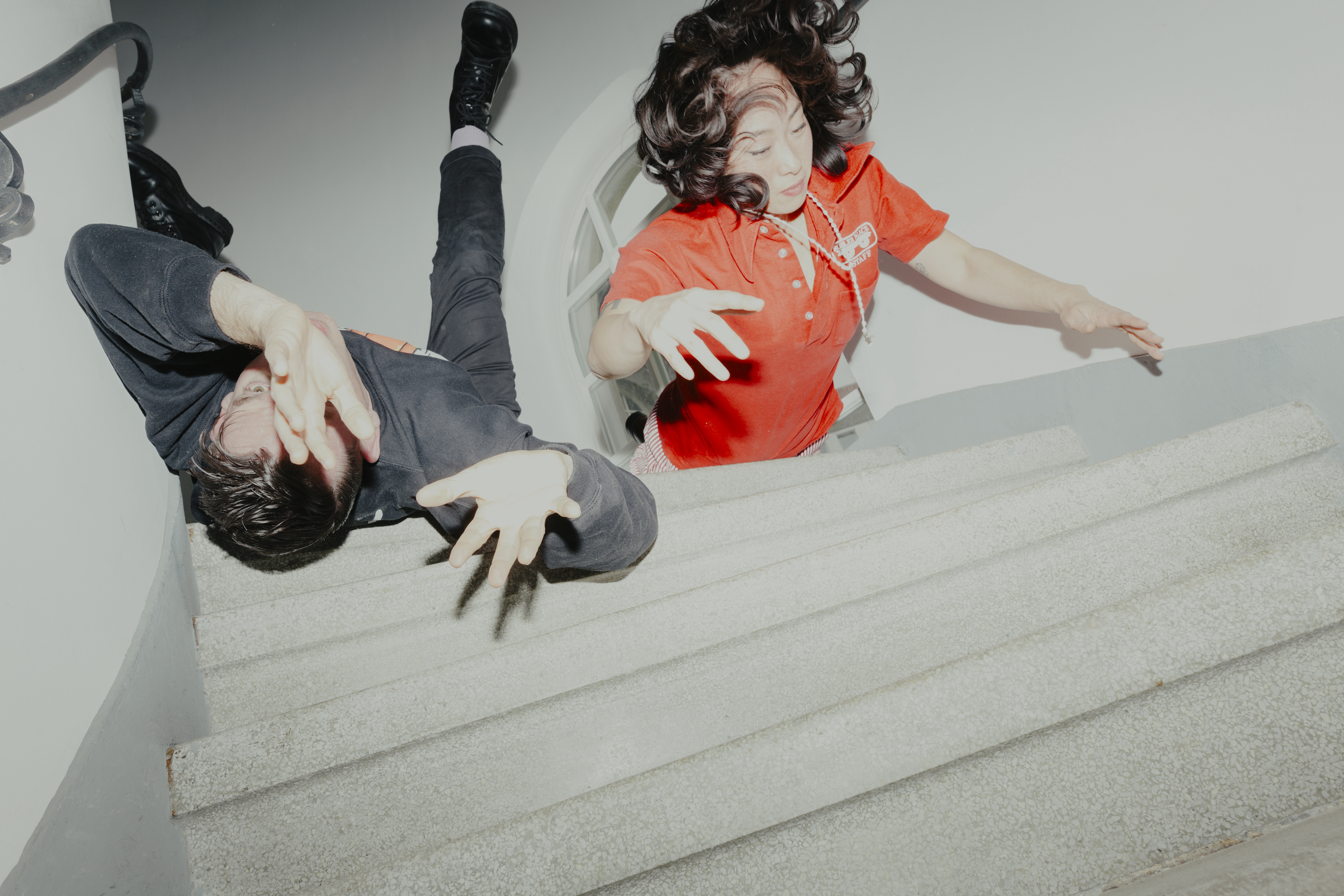 Bilden visar två personer som ser ut att ramla i en ljus trappuppgång.