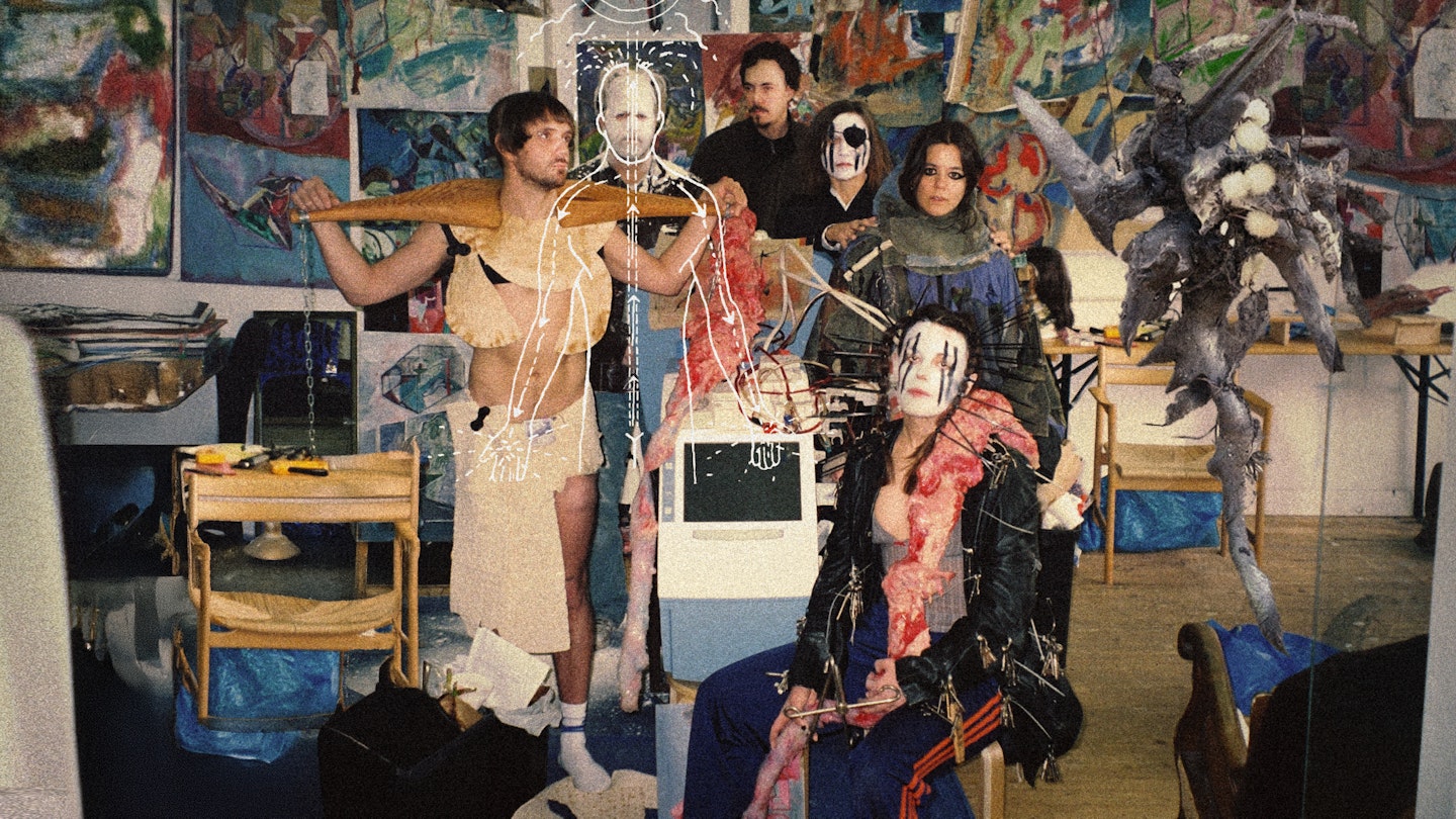 Bilden visar sex personer i olika typer av kostymer och ansiktsmålningar mot en bakgrund av konstmålningar.