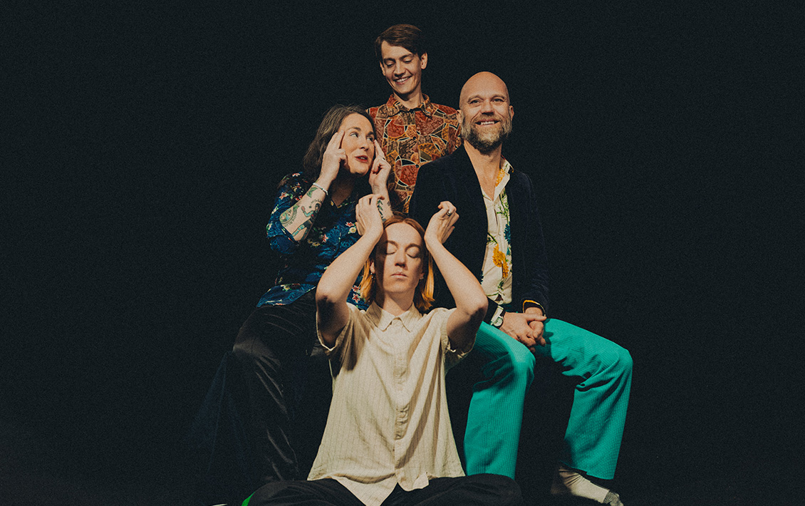 I bild syns fyra personer. En som står, två som sitter på stolar och en som sitter på golvet.