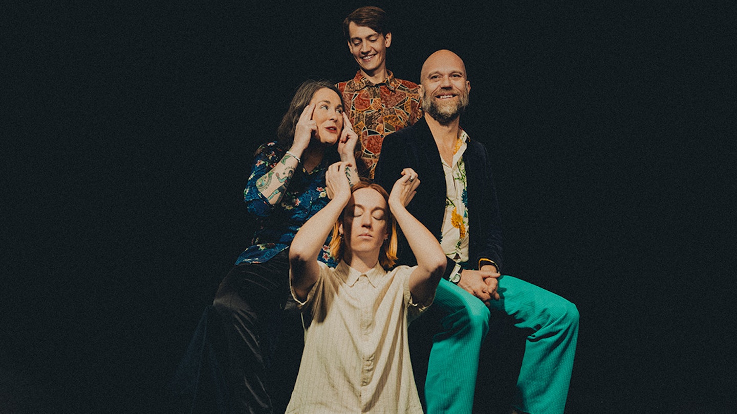 I bild syns fyra personer. En som står, två som sitter på stolar och en som sitter på golvet.