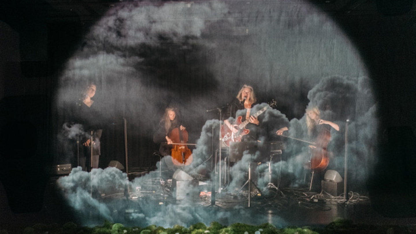 Fotograf: Elakkanin Photography Fyra musiker sitter och spelar i en dimmig miljö.