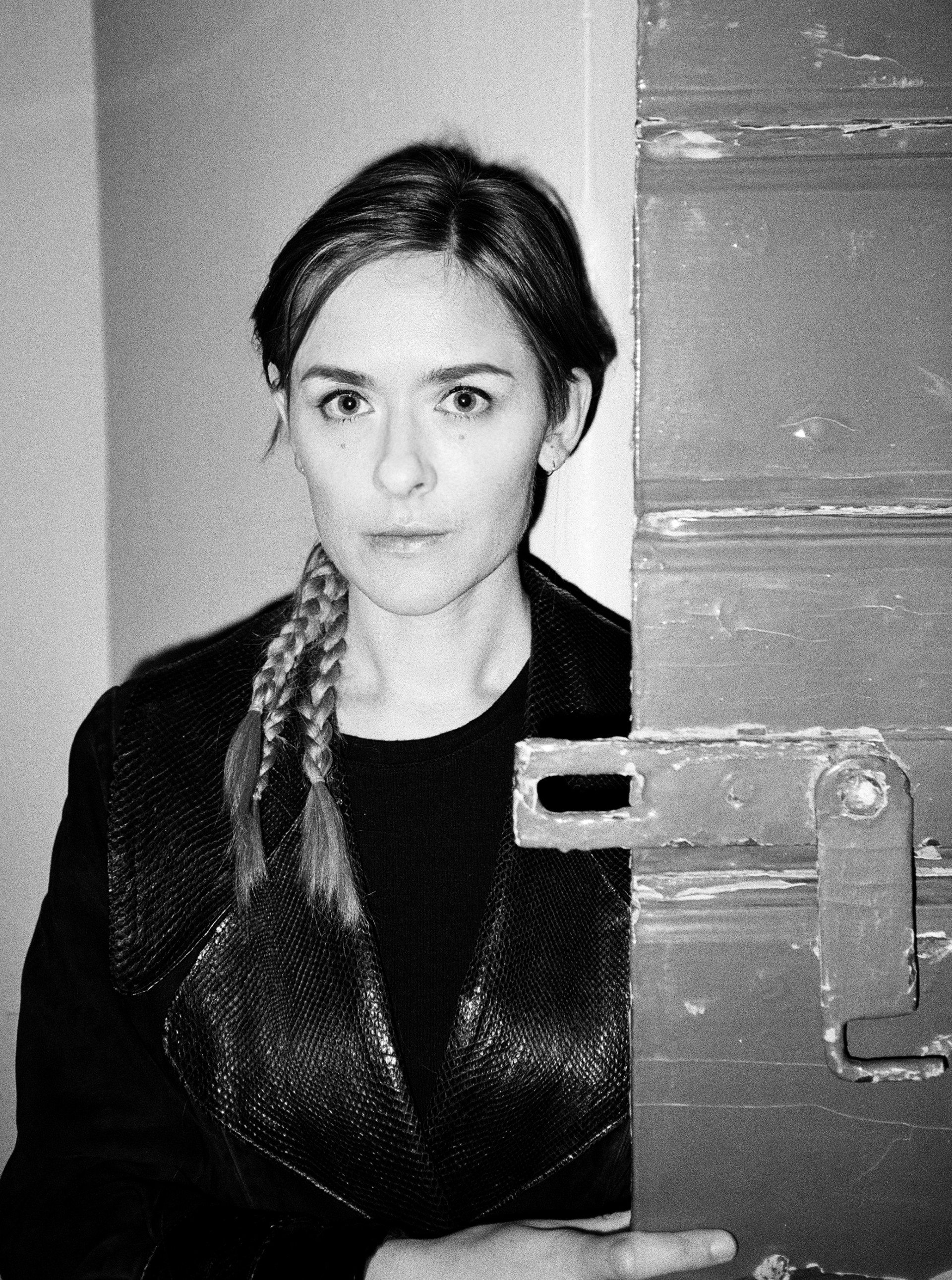 Svartvit närbild på en person som står bredvid en dörr.