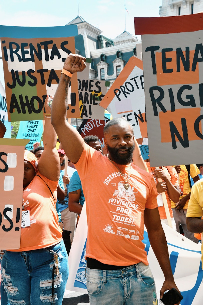picture of tyrone at people's convention rally wearing an orange shirt that says "house everyone."