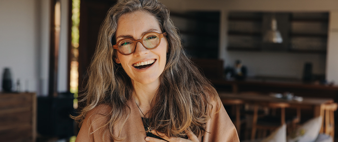 Woman with glasses and brown cardigan smiling