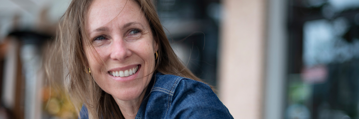 smiling woman with brown hair blowing in wind