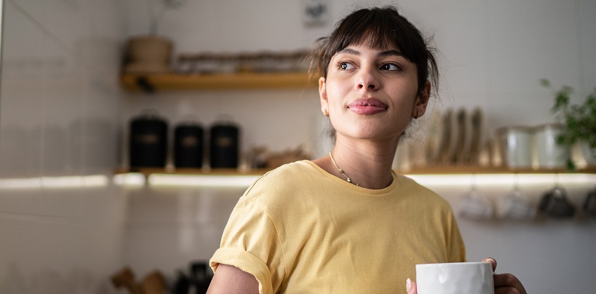 Young woman in kitchen with coffee cup