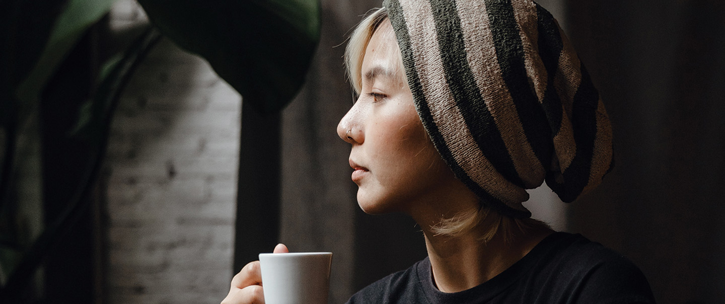 Woman with beanie on drinking cup of coffee