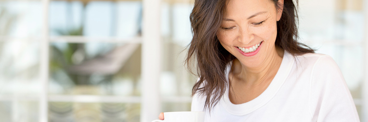 Smiling woman with coffee looking downward
