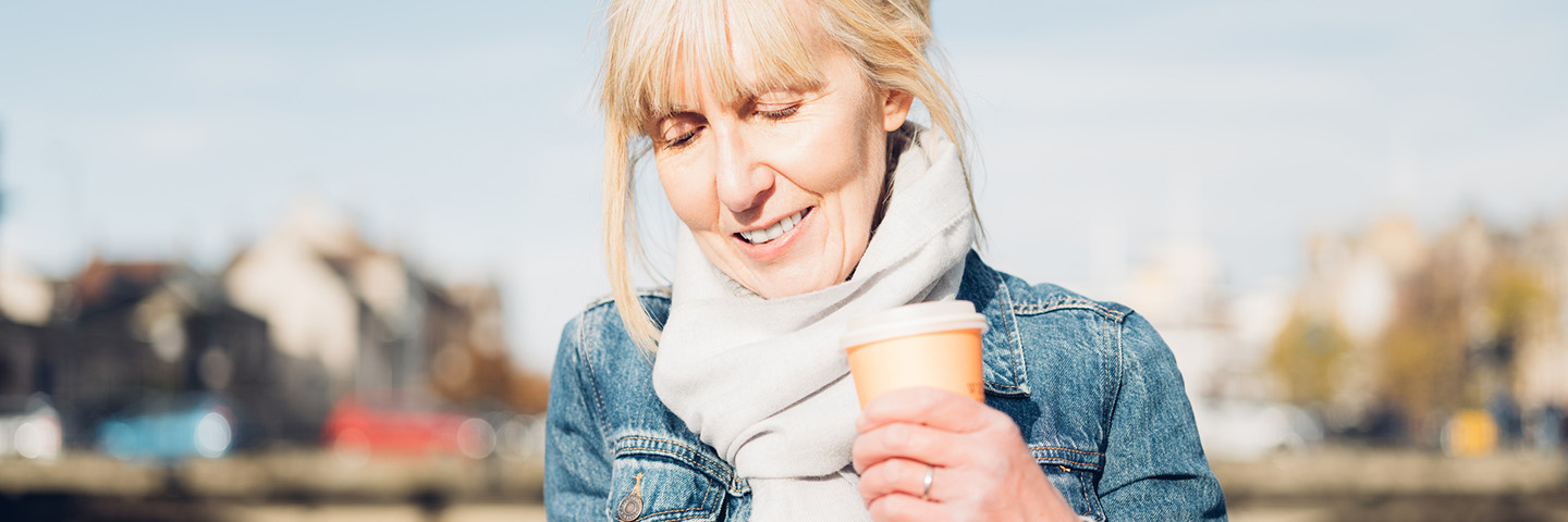 Woman wearing denim jacket holding coffee cup