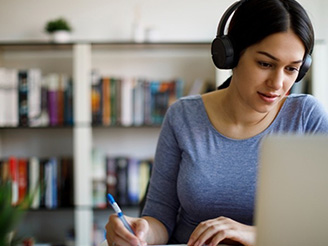 Woman with headphones on using Macbook