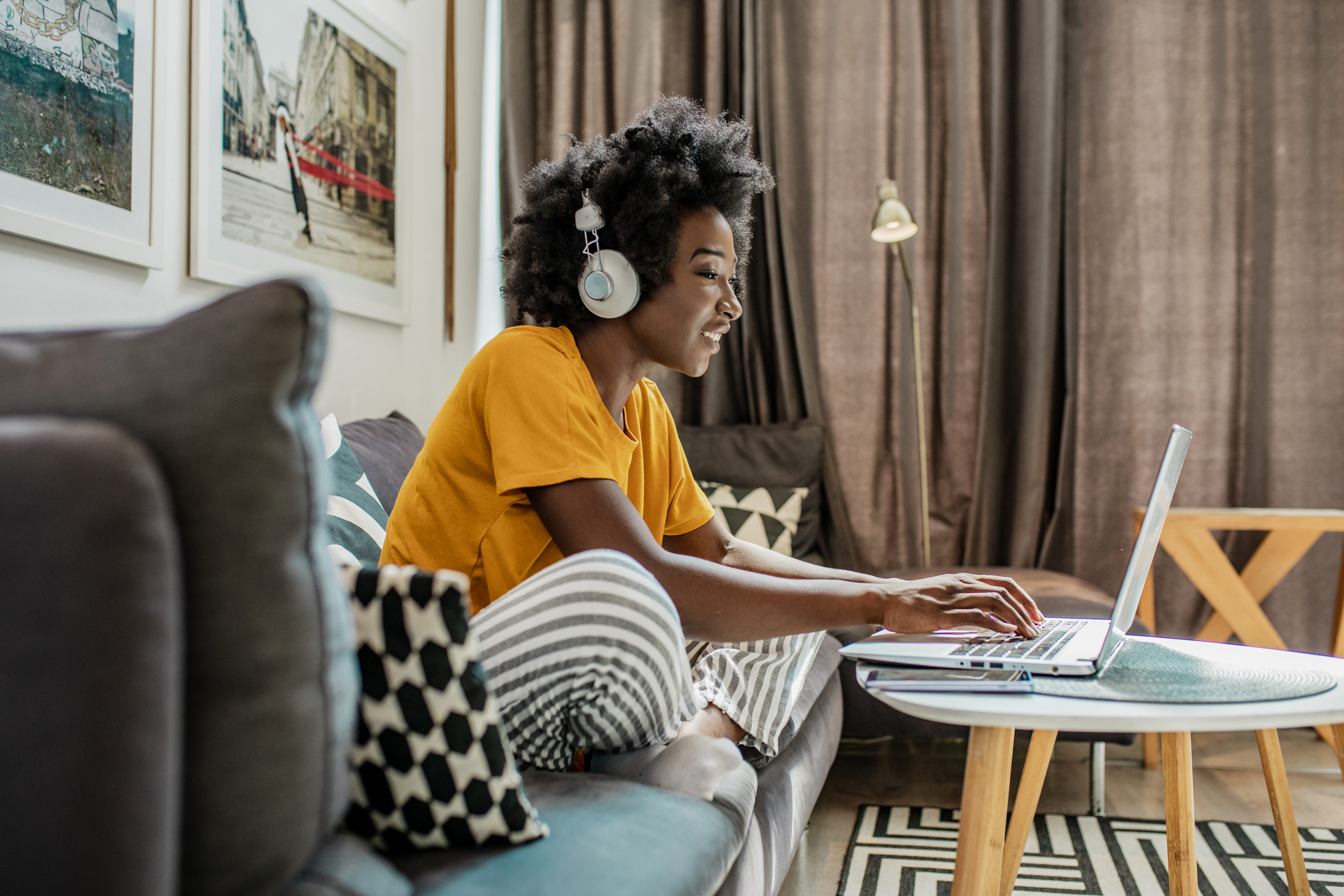 Woman with yellow t-shirt on couch using laptop