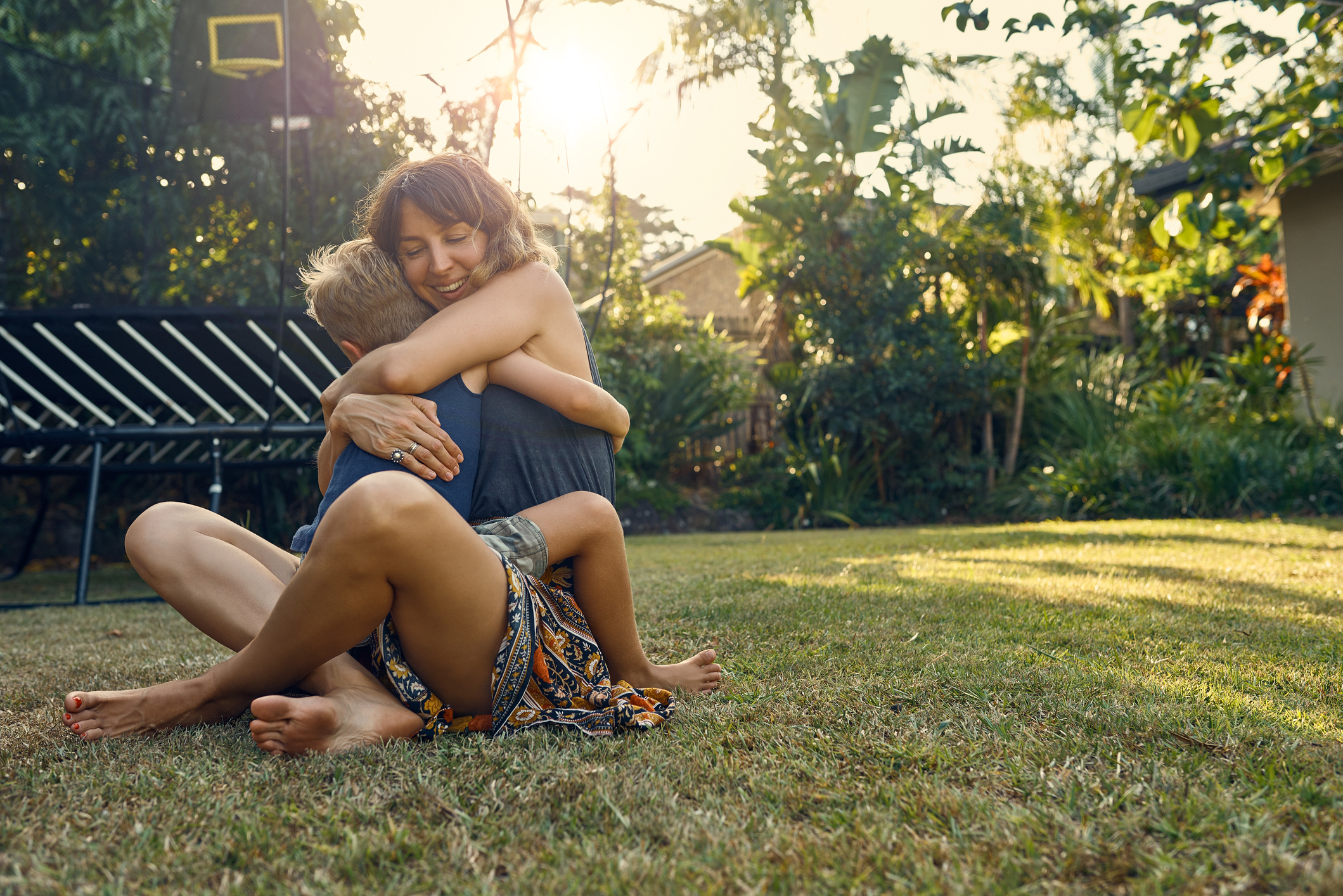 Mother hugging toddler in backyard