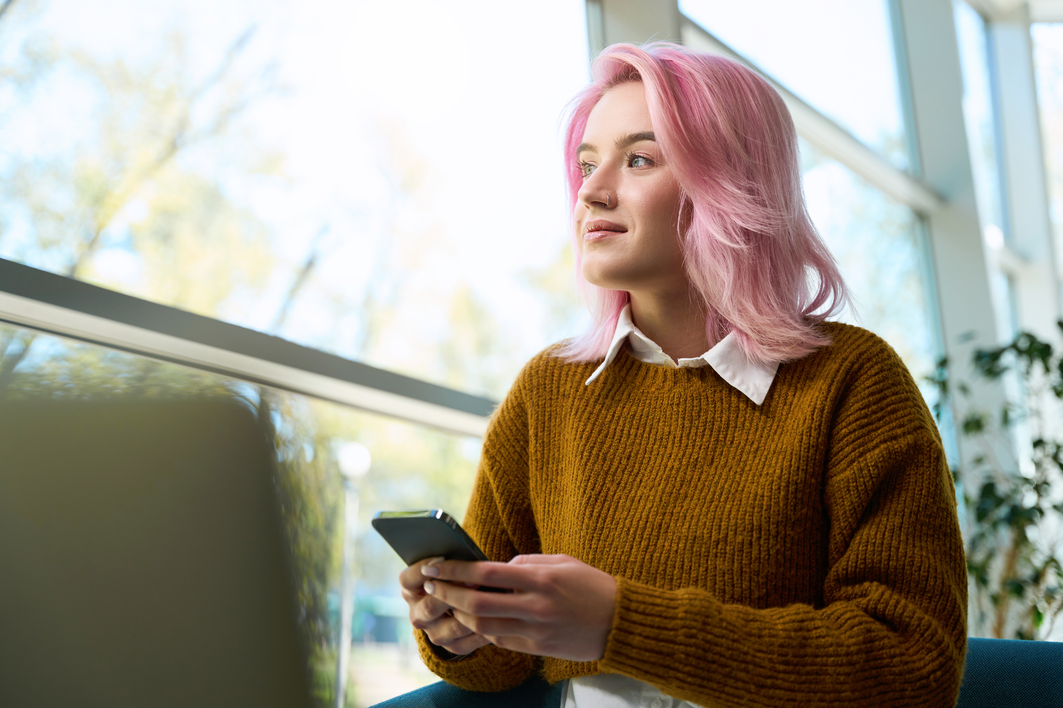 Woman with pink hair looking out the window